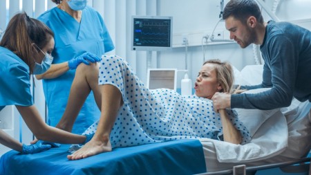 Une sage-femme: assiste au moment de l'accouchement